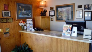 A reception desk with framed artwork, a clock, and informational brochures. - Evergreen Studios (Sheridan)