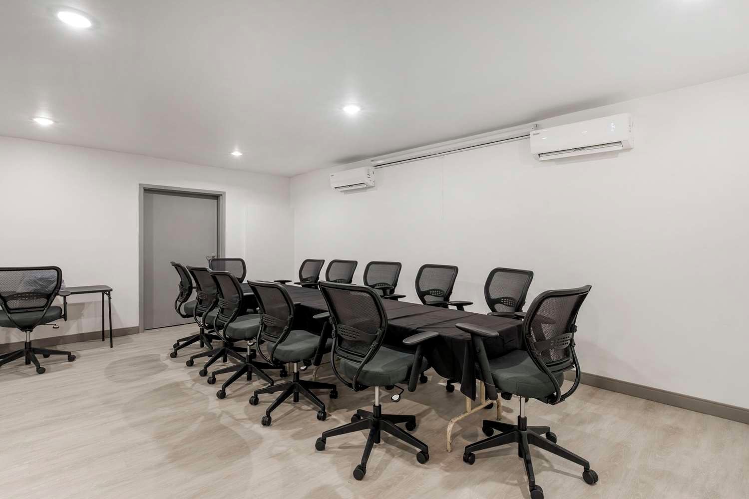 A conference room with a long table and chairs, an air conditioning unit, and a door.