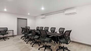 A conference room with a long table and chairs, an air conditioning unit, and a door.