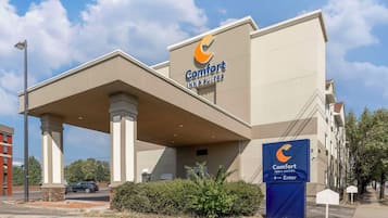 A Comfort Inn & Suites hotel with a modern facade, a covered entrance, and a clear sky.