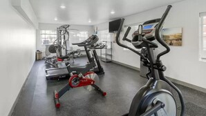 A gym with cardio equipment, a TV, and large windows.