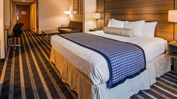 Una habitación de hotel con una cama grande, un escritorio, una silla y una lámpara.