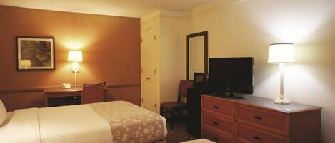 A hotel room with two beds, a desk, a chair, a dresser, a television, and two wall-mounted lamps.