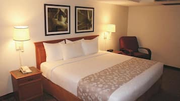 A hotel room with a bed, two wall-mounted lamps, a chair, and a telephone on a nightstand.