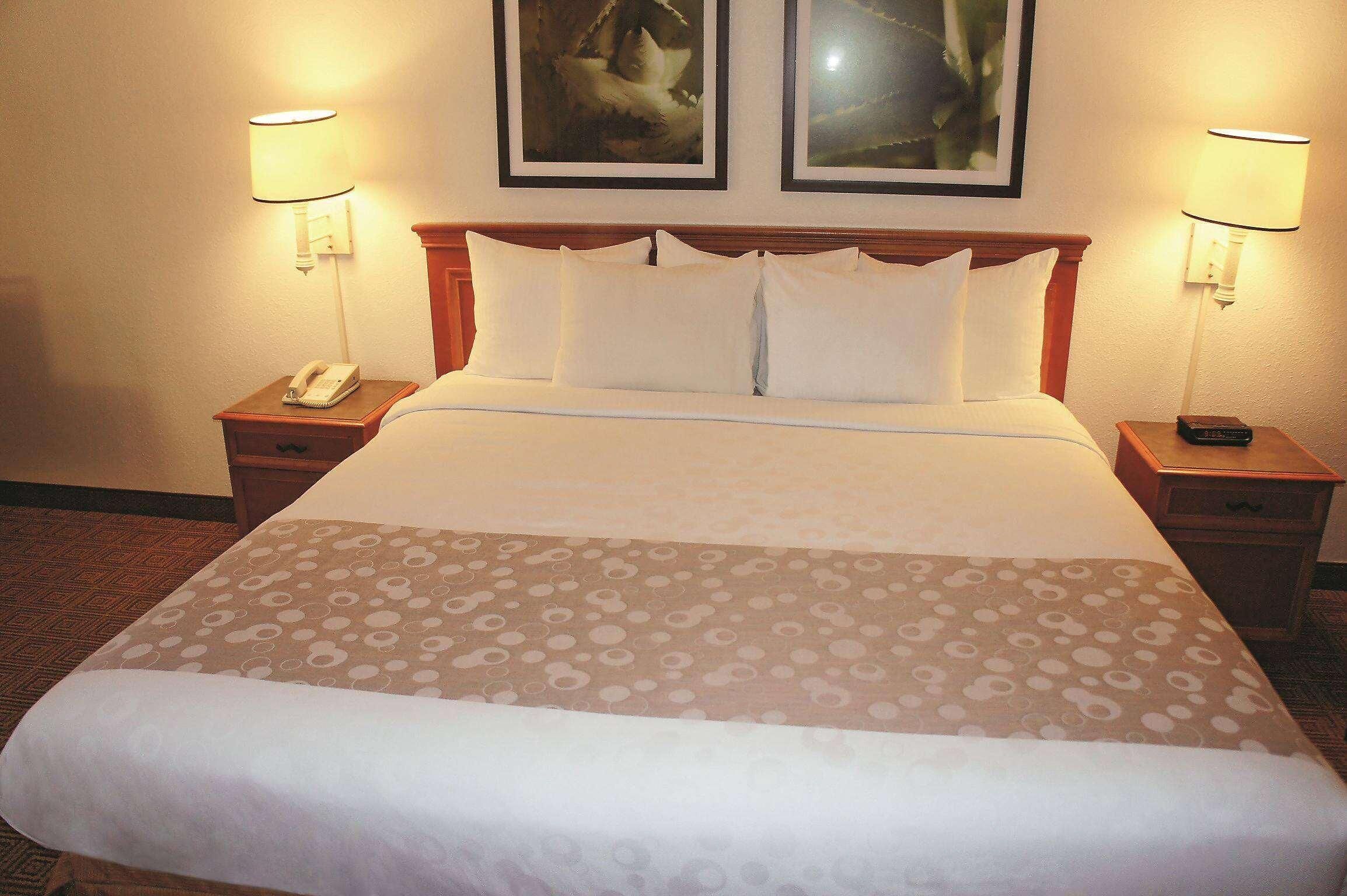 Une chambre d’hôtel comprenant un lit, deux tables de chevet, un téléphone et deux lampes fixées au mur.
