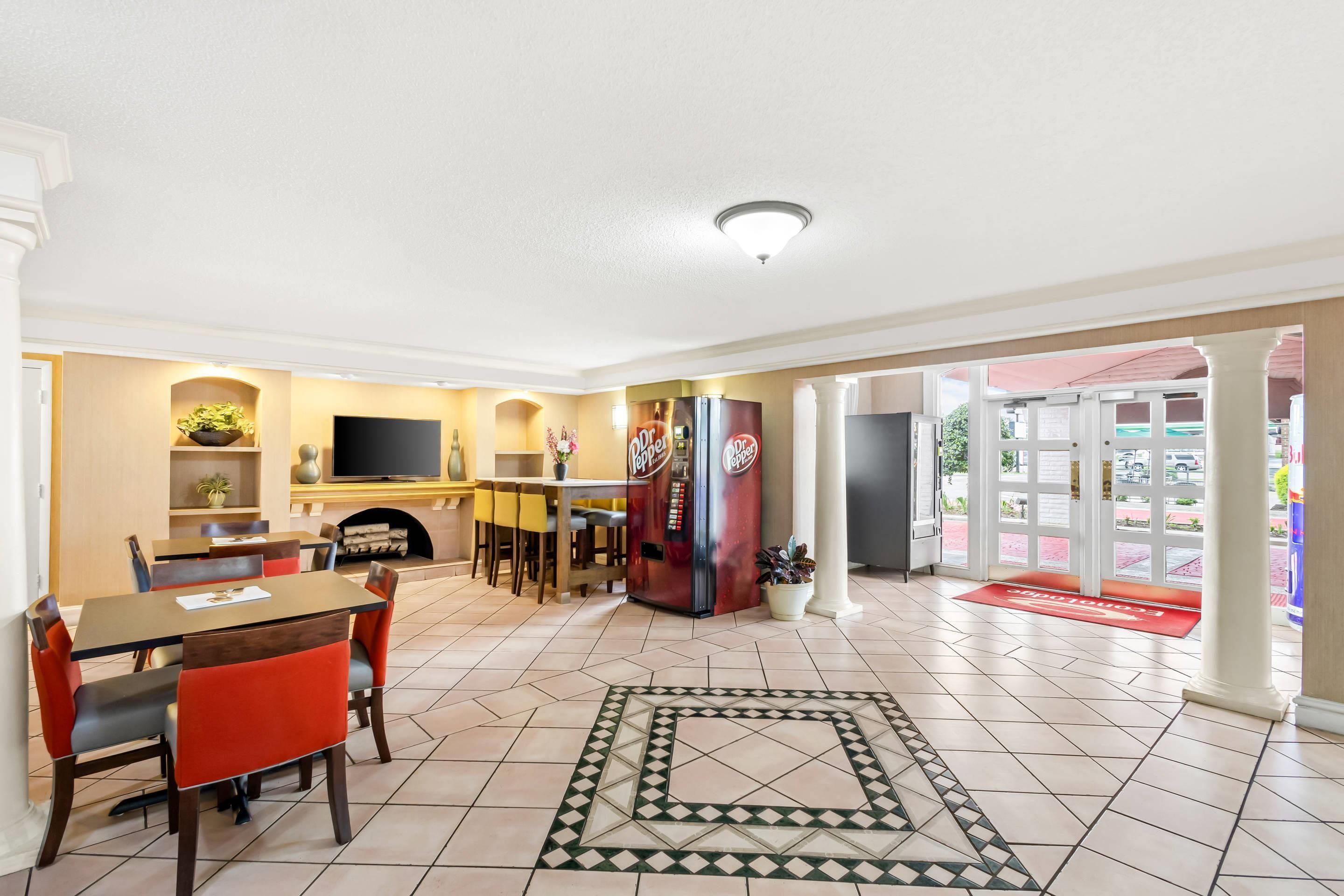 Un hall de hotel con comedor, cocina, televisor y refrigerador.