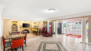 Un hall de hotel con comedor, cocina, televisor y refrigerador.