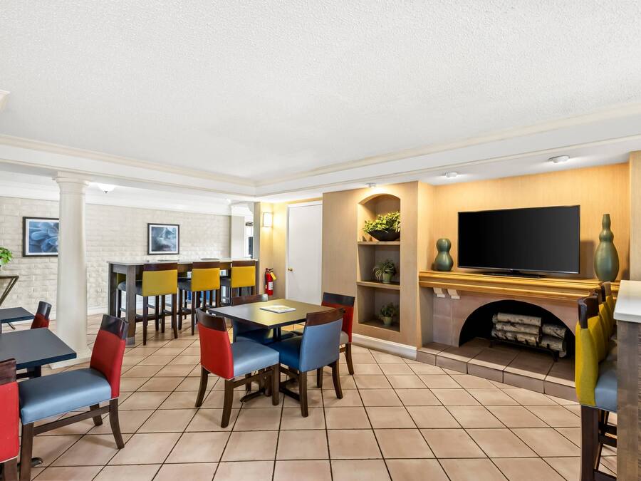 A dining area with a fireplace, a television, and a kitchen in the background.