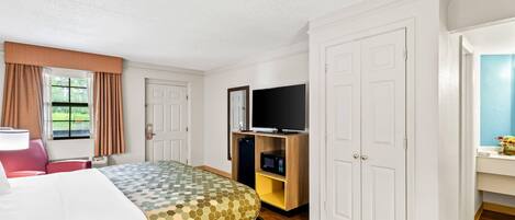 A hotel room with a bed, a TV, a microwave, and a wardrobe.