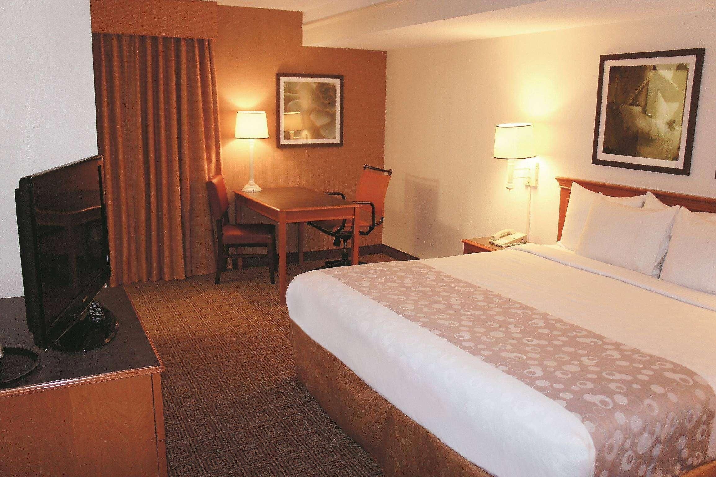 Una habitación de hotel con cama, escritorio, silla y televisor.