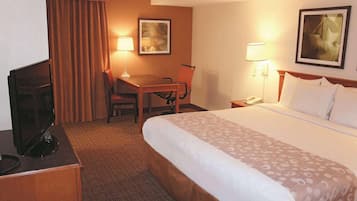 Una habitación de hotel con cama, escritorio, silla y televisor.