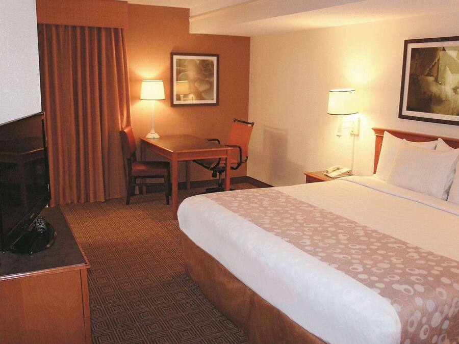 A hotel room with a bed, desk, chair, and a television.