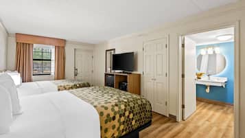 Habitación de hotel con dos camas, televisor, baño con lavabo y espejo, y ventana con cortinas.