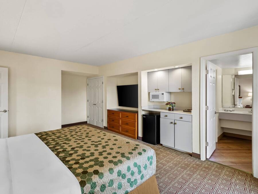 Een hotelkamer met een bed, een kitchenette, een televisie en een badkamer.