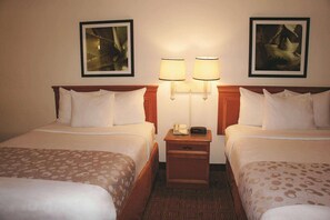 A hotel room with two beds, a nightstand with a lamp, and two framed pictures on the wall. - Econo Lodge Augusta North - Washington Road (Augusta)