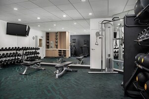 A gym with weightlifting equipment, benches, and a mirrored wall.