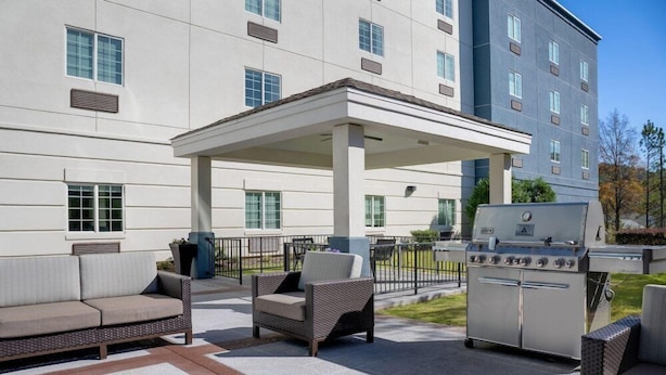 An outdoor patio area with a covered seating area, a grill, and a building in the background. - Towneplace Suites by Marriott Birmingham South (Birmingham)