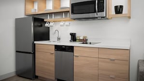 A modern kitchen with a stainless steel refrigerator, a microwave, and a dishwasher. There are wooden cabinets and a white countertop. - Towneplace Suites by Marriott Birmingham South (Birmingham)
