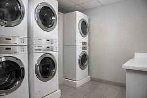 Una sala de lavandería con lavadoras y secadoras de carga frontal apiladas.