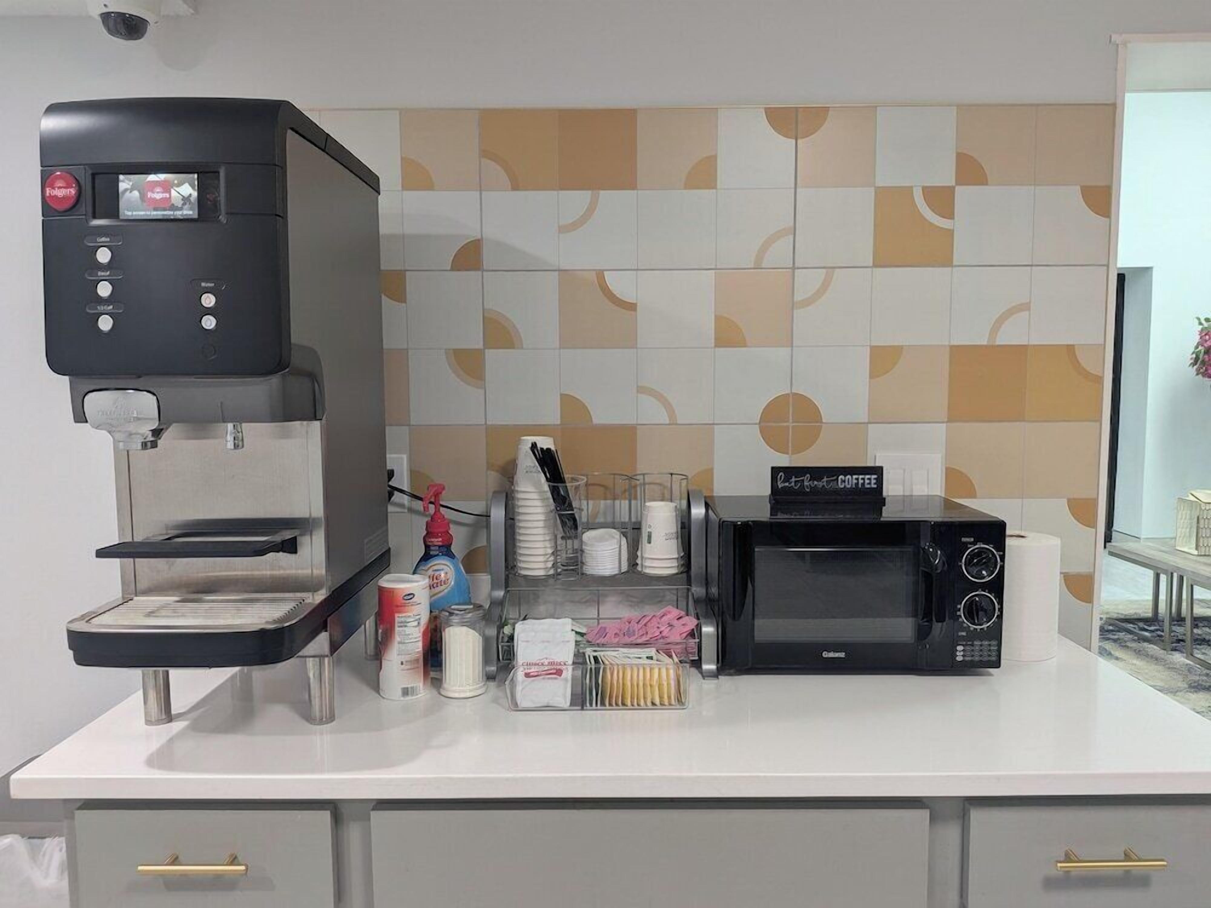 A coffee station with a coffee machine, a microwave, and various coffee-making accessories on a counter.