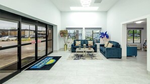 A spacious lobby with a reception desk, two sofas, a coffee table, and a large window offering a view of the parking lot. - Days Inn & Suites by Wyndham Bossier City (Bossier City)