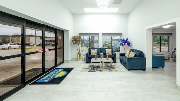 A spacious lobby with a reception desk, two sofas, a coffee table, and a large window offering a view of the parking lot. - Days Inn & Suites by Wyndham Bossier City (Bossier City)