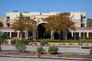A hotel with a large archway entrance, a prominent logo, and a landscaped front yard. - Comfort Suites Baton Rouge South I-10 (Baton Rouge)