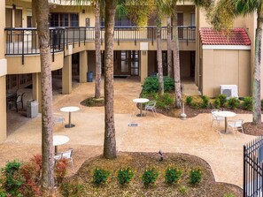 A courtyard with multiple levels, outdoor seating areas, and palm trees. - Comfort Suites Baton Rouge South I-10 (Baton Rouge)