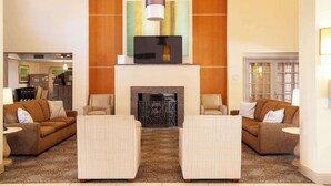 A lobby with two sofas, a fireplace, and a modern art piece above it. - Comfort Suites Baton Rouge South I-10 (Baton Rouge)