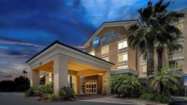 Un hôtel Best Western doté d’une entrée couverte, de palmiers et offrant une vue sur un ciel dégagé.