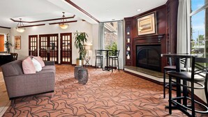 Un salon spacieux avec une cheminée, un canapé gris et un tapis à motifs.