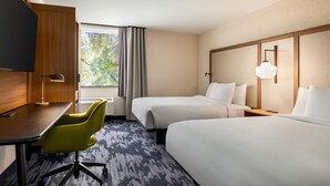 A hotel room with two beds, a desk with a chair, a TV, and a window with curtains. - Hotel Monona (Madison)