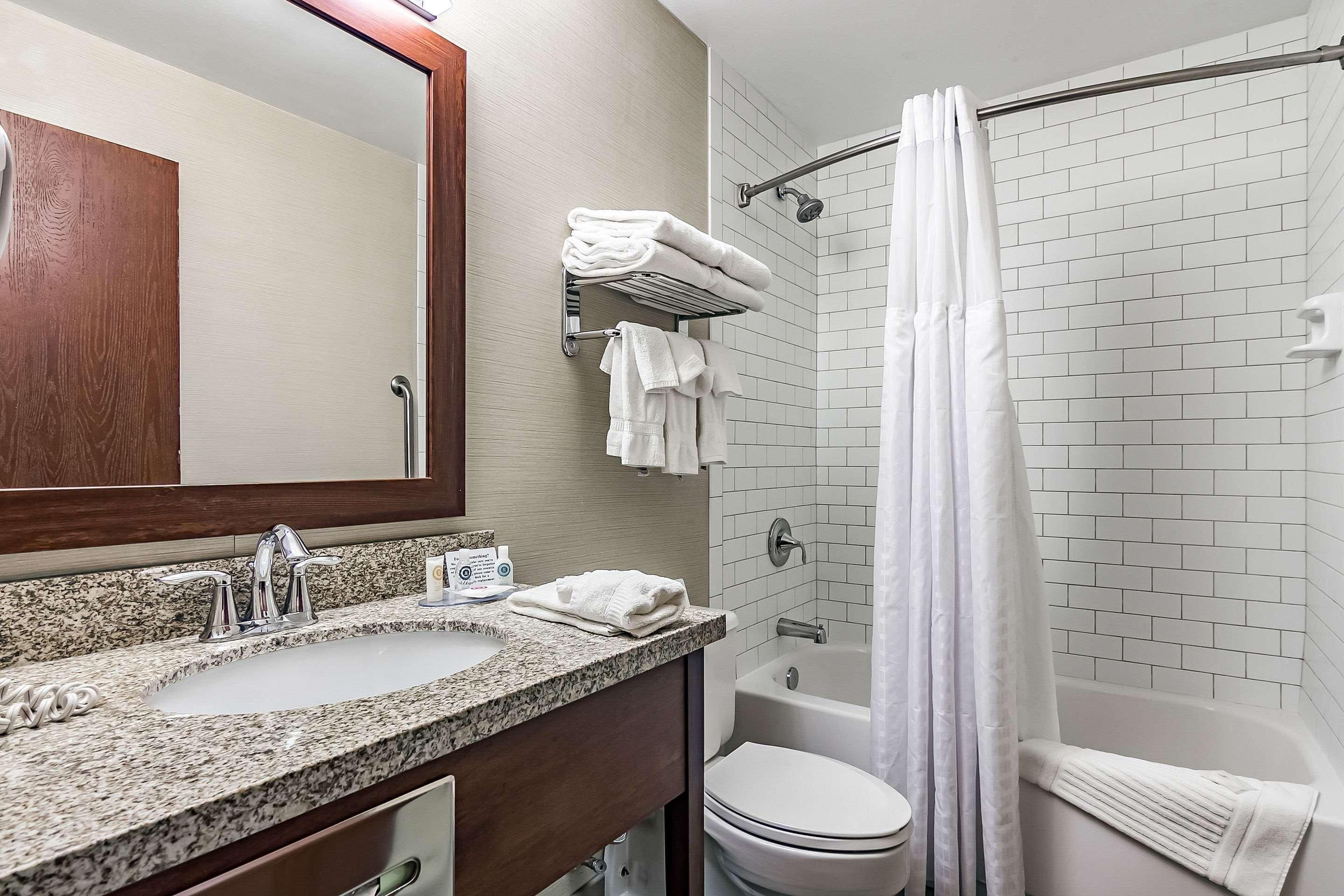 A bathroom with a sink, mirror, towel rack, toilet, and shower area.