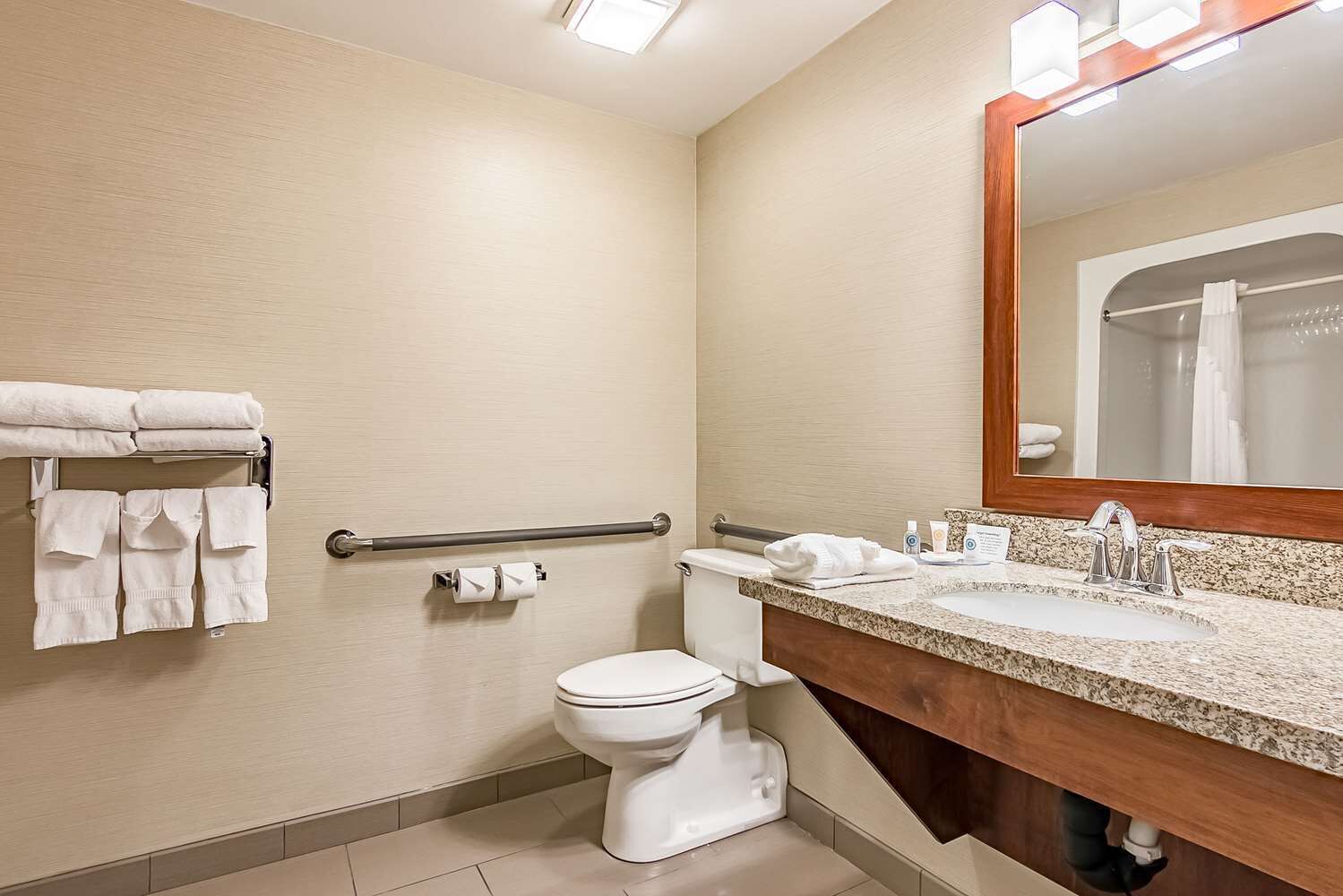 A bathroom with a toilet, a sink with a mirror, and a towel rack with towels.