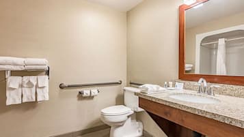 A bathroom with a toilet, a sink with a mirror, and a towel rack with towels.