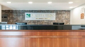 A reception desk at Quality Inn by Choice Hotels with a stone wall backdrop and a wooden counter. - Fairbridge Inn Express Indianapolis Northwest (Indianapolis)