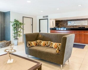 Een receptie met een bank, een receptiebalie en een bord met daarop Quality Inn by Choice Hotels.