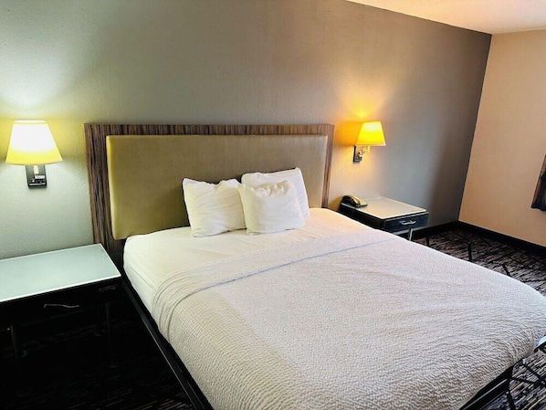 Una habitación de hotel con una cama, dos mesitas de noche y dos lámparas de pared.