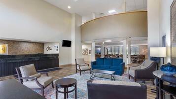 A hotel lobby with a reception desk, seating area, and a dining space.