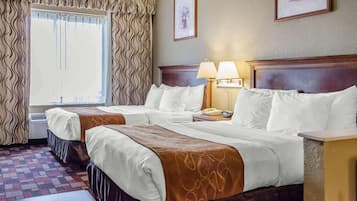 Une chambre d’hôtel avec deux lits, une fenêtre avec des rideaux, un tableau encadré au mur et une table de chevet avec une lampe.