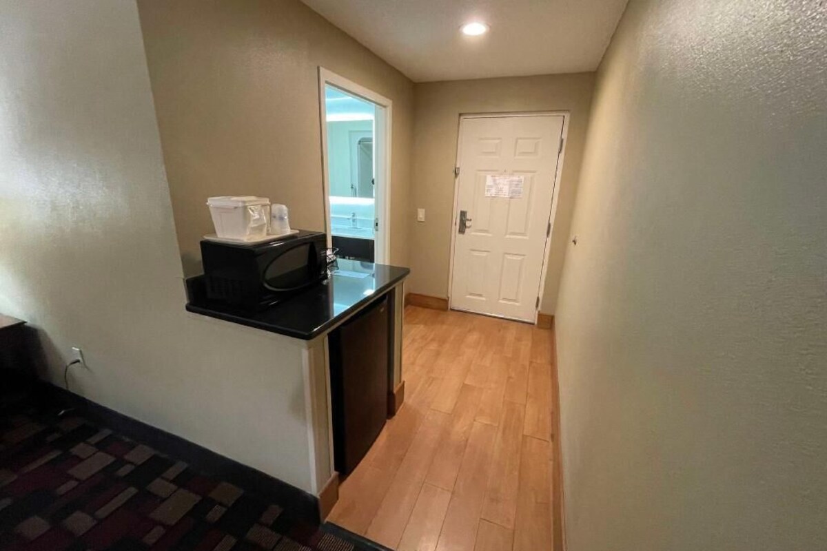 A hallway with a microwave on a black countertop, a white door, and a patterned carpet.