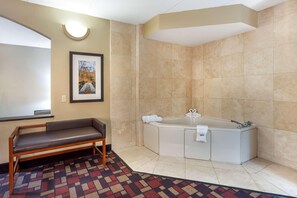 A bathroom with a bench, a bathtub, and a framed picture on the wall. - Best Western Grantville/hershey (Grantville)