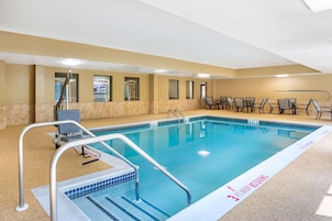 Piscina con zona de clavados de 90 centímetros de profundidad, rodeada de sillas y mesas.