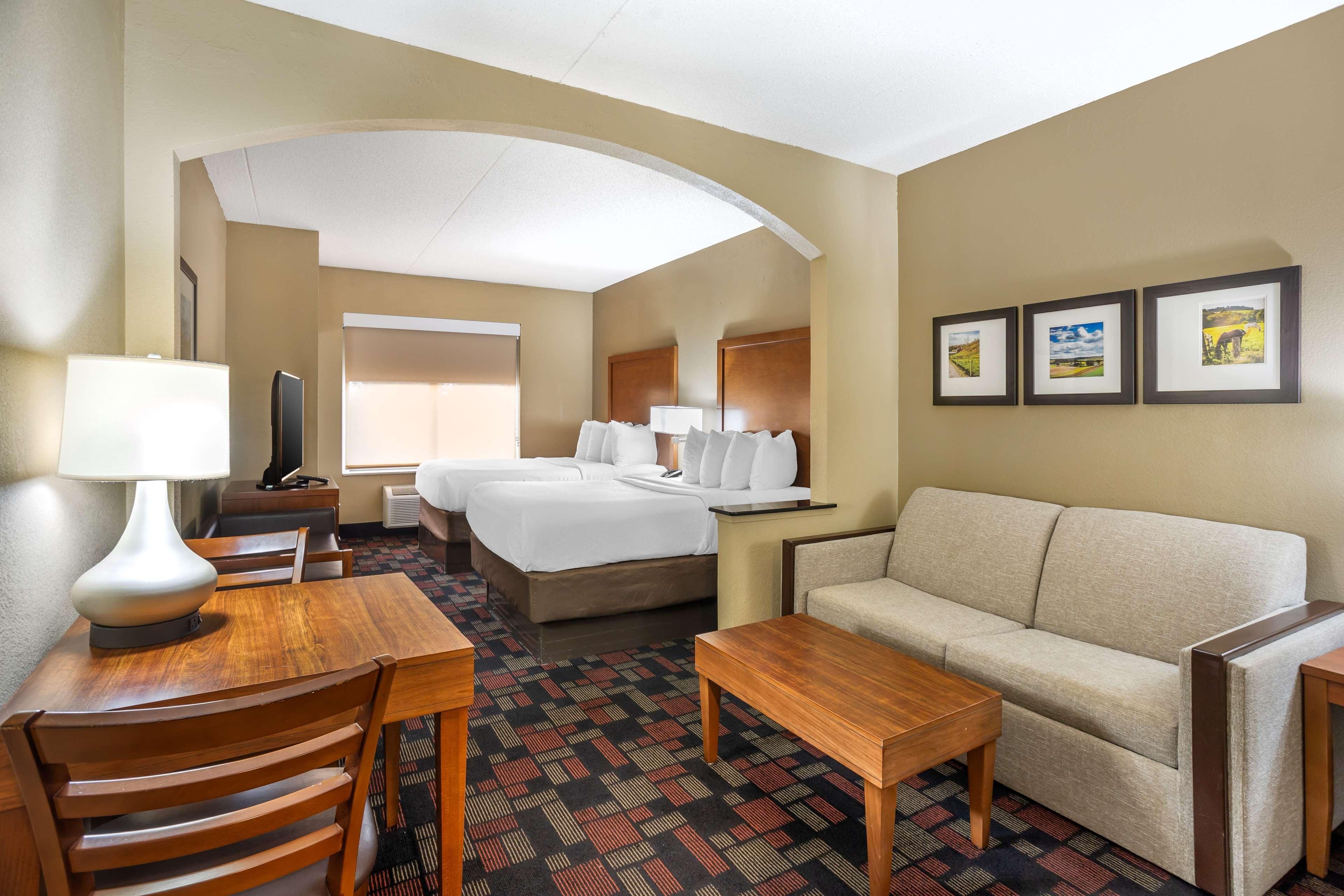 Ein Hotelzimmer mit Bett, Sofa, Esstisch, Stühlen und einem Fernseher.