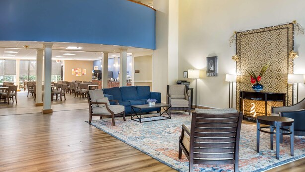 Un hall d’hôtel avec un mur d’accent bleu, un tapis à motifs et une cheminée agrémentée d’objets décoratifs.