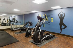 Un gimnasio con máquinas de cardio, un espejo grande y frases motivacionales en la pared.