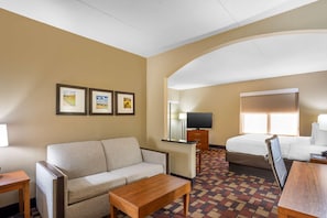 A hotel room with a sofa, a wooden table, a bed, a TV, and framed pictures on the wall. - Best Western Grantville/hershey (Grantville)