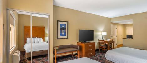 A hotel room with two beds, a desk, a chair, a television, and a framed picture on the wall.