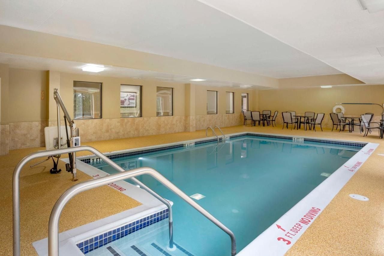 Une piscine intérieure dont la partie la plus profonde mesure environ 90 cm, entourée de chaises et dotée d’un sol carrelé.