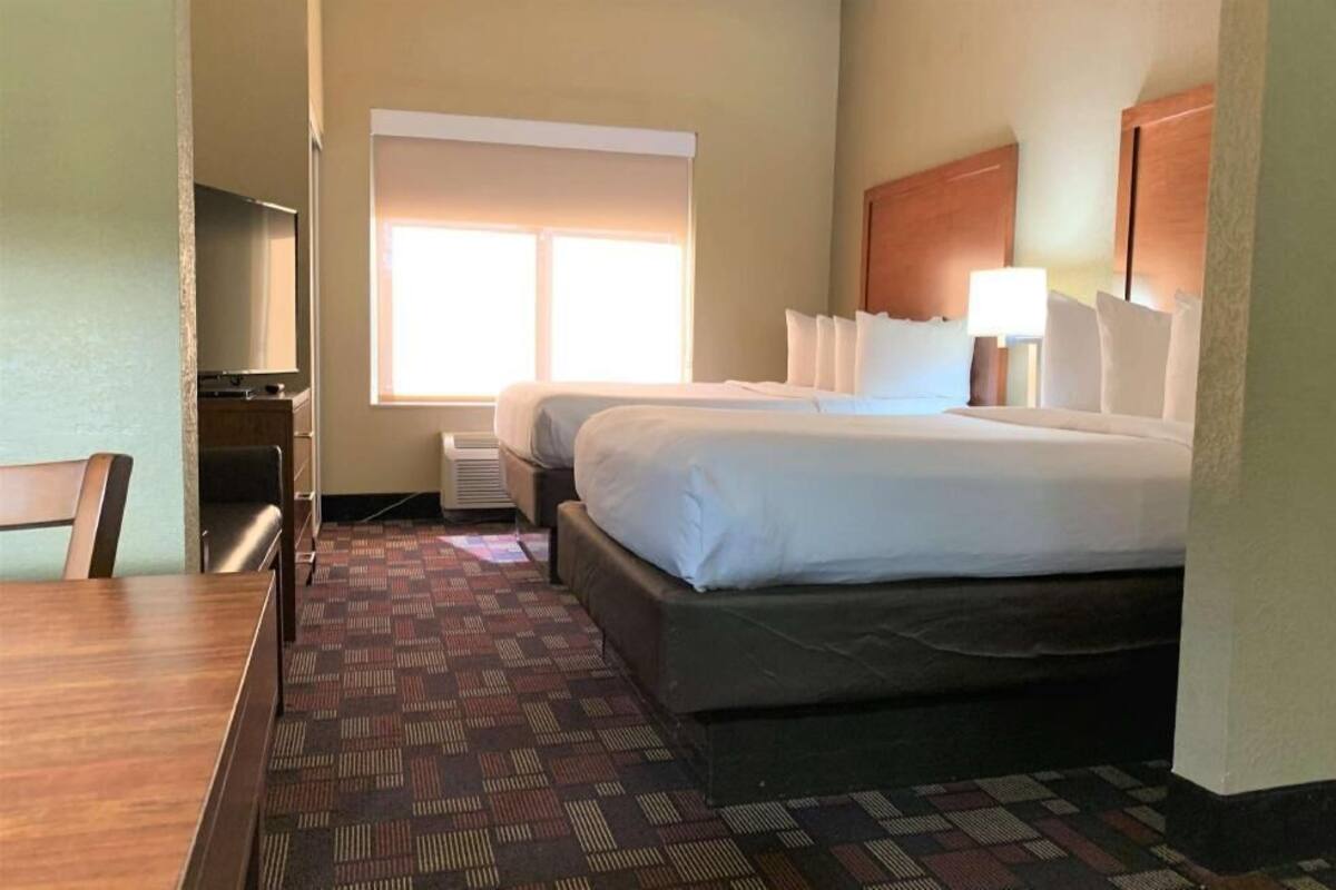 A hotel room with a bed, a desk, a chair, a TV, and a window.